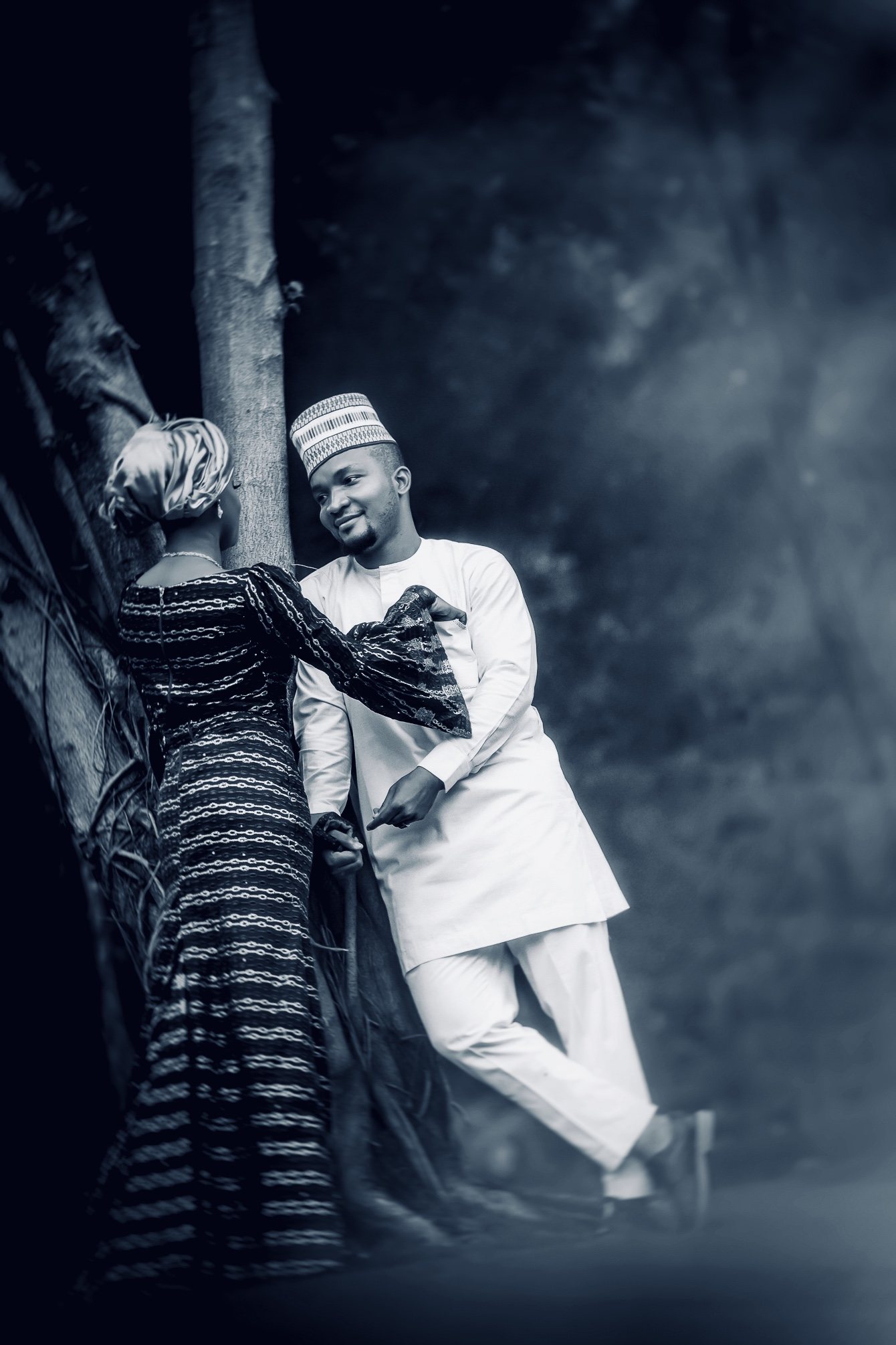 Bride and groom leaning together against a tree, black and white